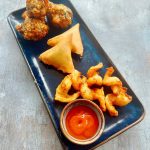 some lamb samosa, wings and fried prawns on a plate in Potyo Wilmslow